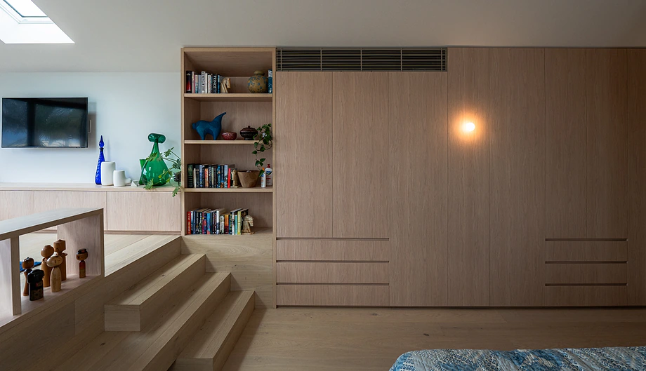 Custom wardrobes Sydney: built-in timber wardrobe wall with integrated bookshelves in a bedroom