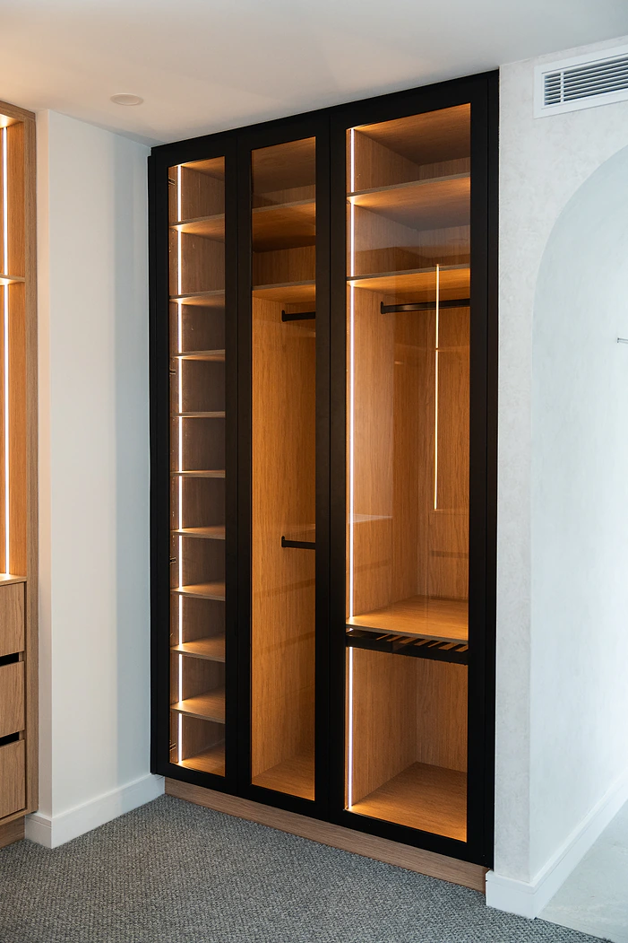 Black framed glass wardrobe doors with lit timber interior