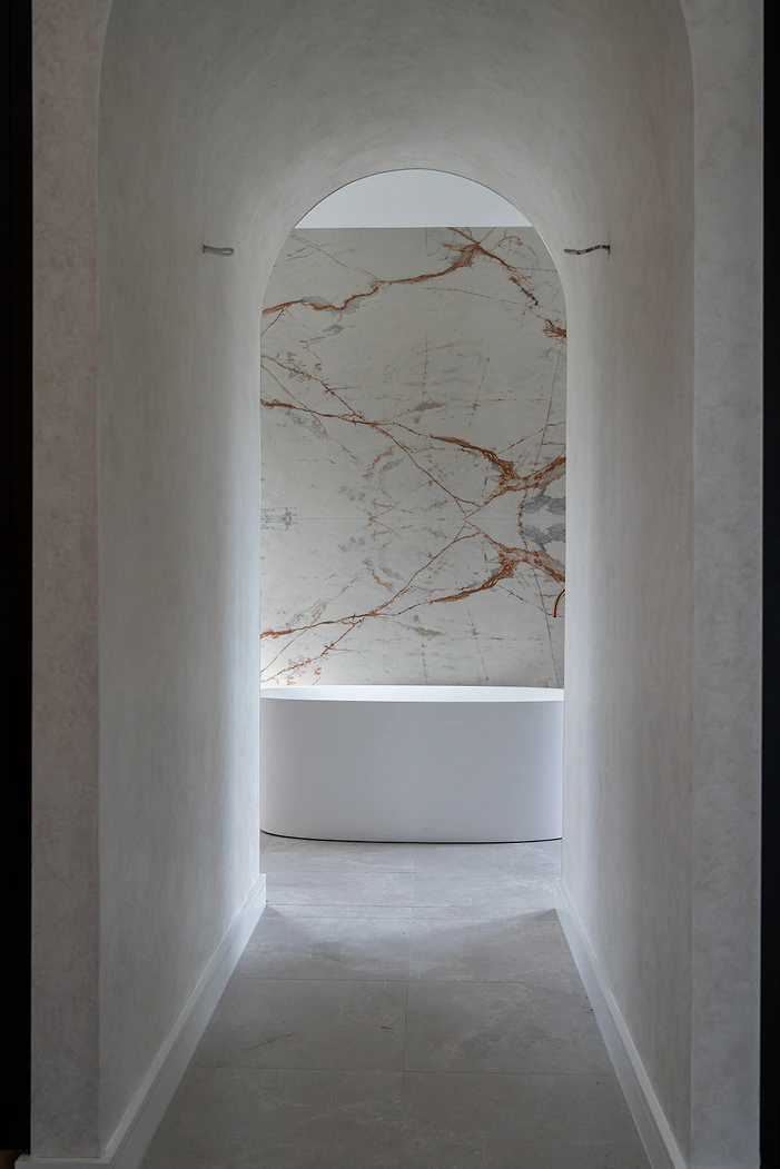 Arched hallway leading to an ensuite with freestanding bath
