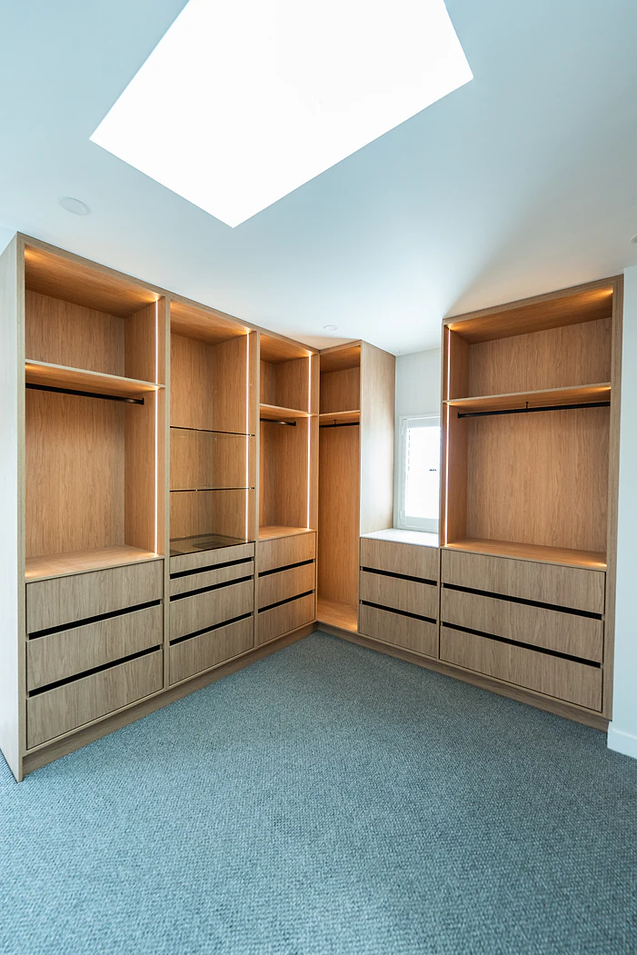 Spacious walk-in wardrobe under a skylight with timber cabinetry