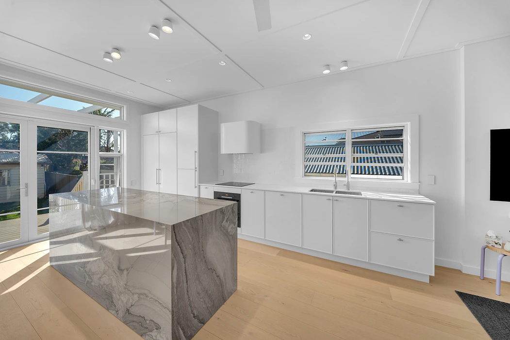 Bright white kitchen with waterfall stone island and timber floors