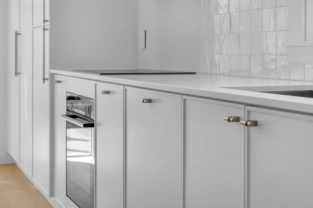 White shaker cabinetry with integrated oven and stone benchtop