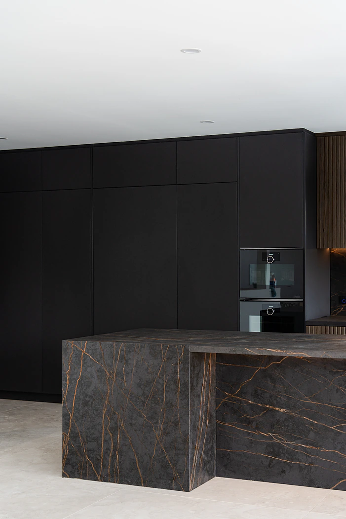 Black kitchen with dark stone waterfall island bench
