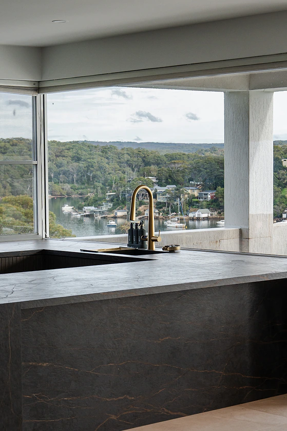 Dark stone kitchen island with brass tap overlooking the water