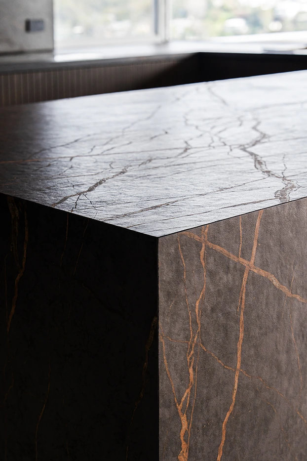 Mitred edge of a dark stone waterfall benchtop