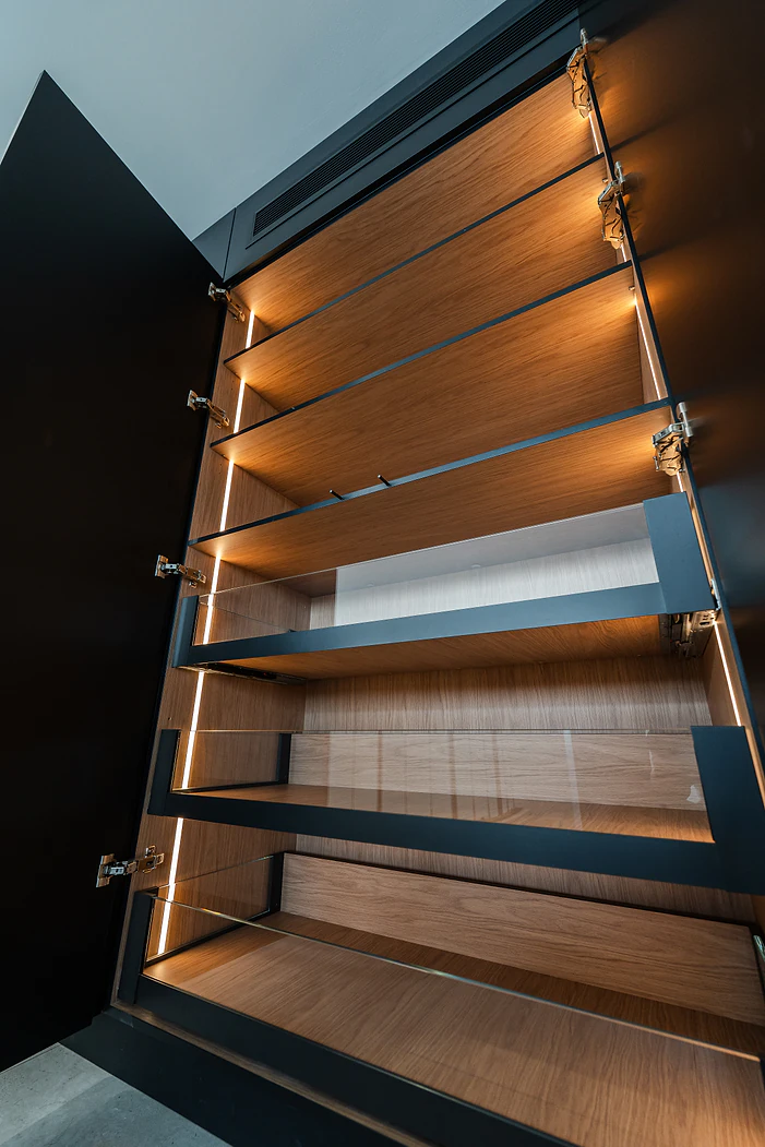 Lit timber pantry shelving inside a black cabinet