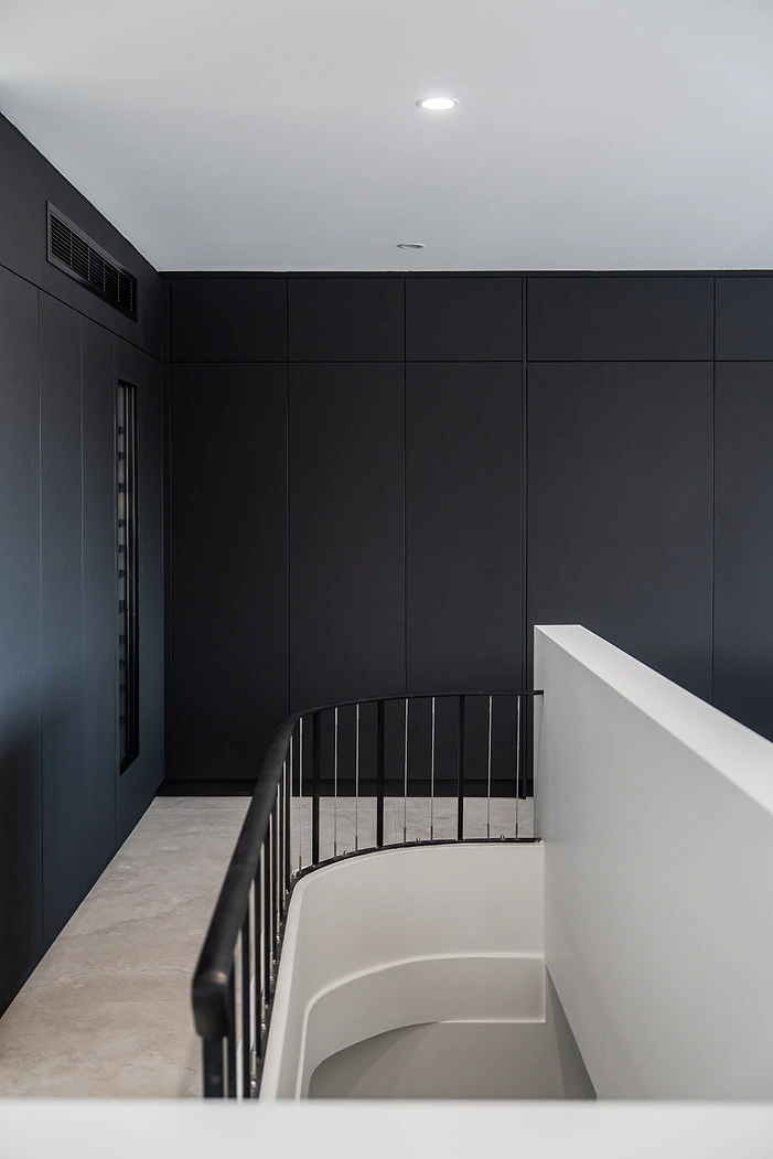 Black kitchen cabinetry beside a curved staircase