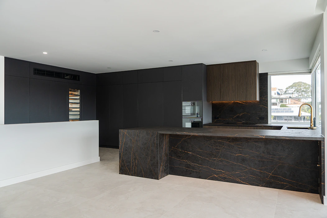 Custom kitchens Sydney: luxury black kitchen with dark stone island and fluted timber rangehood