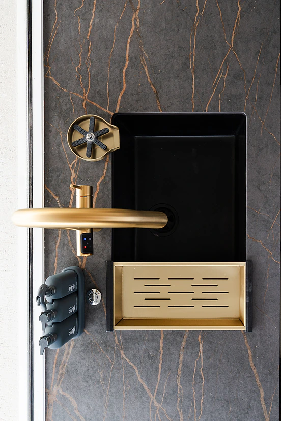 Brass tap and undermount sink in dark stone benchtop