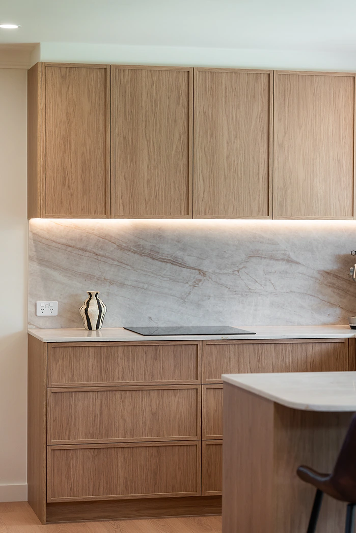 Timber kitchen cabinetry with lit marble splashback