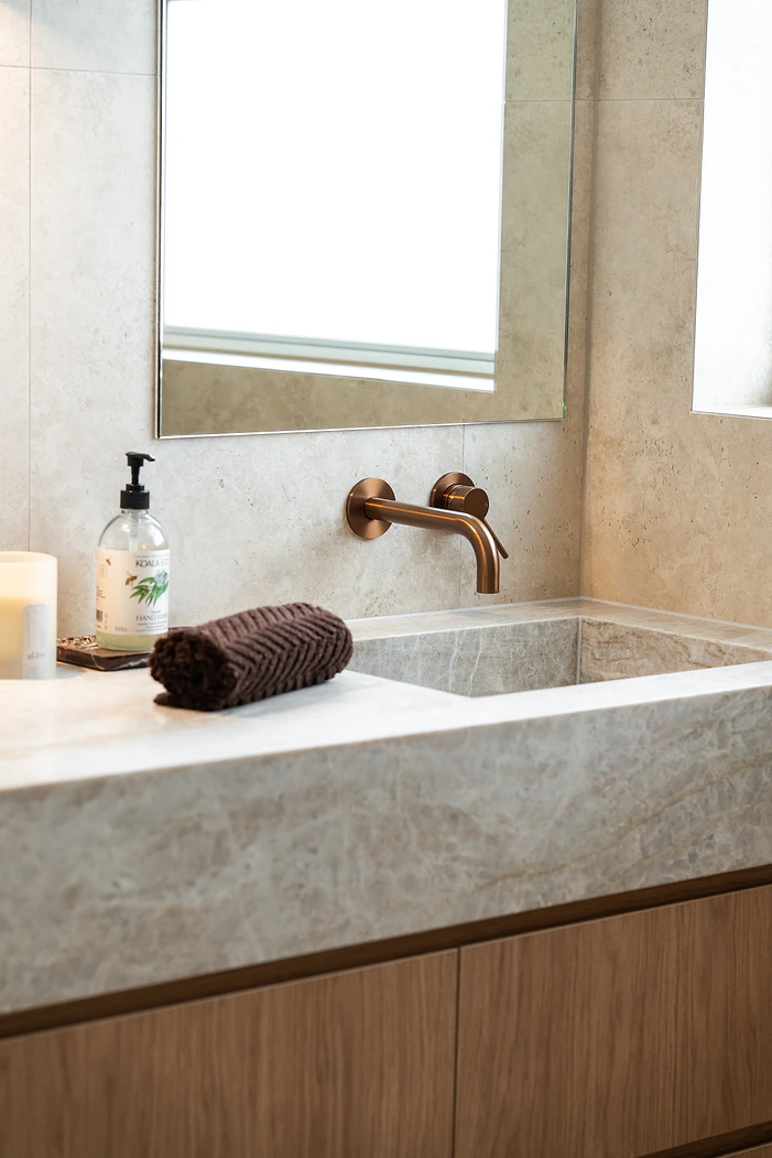 Stone basin and timber vanity with copper tapware